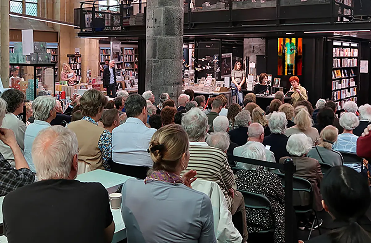 Mensen zitten op stoelen te kijken naar boekpresentatie van Maria Philiipens in boekhandel Dominicanen Maastricht